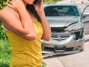 girl on the phone in front of wrecked car